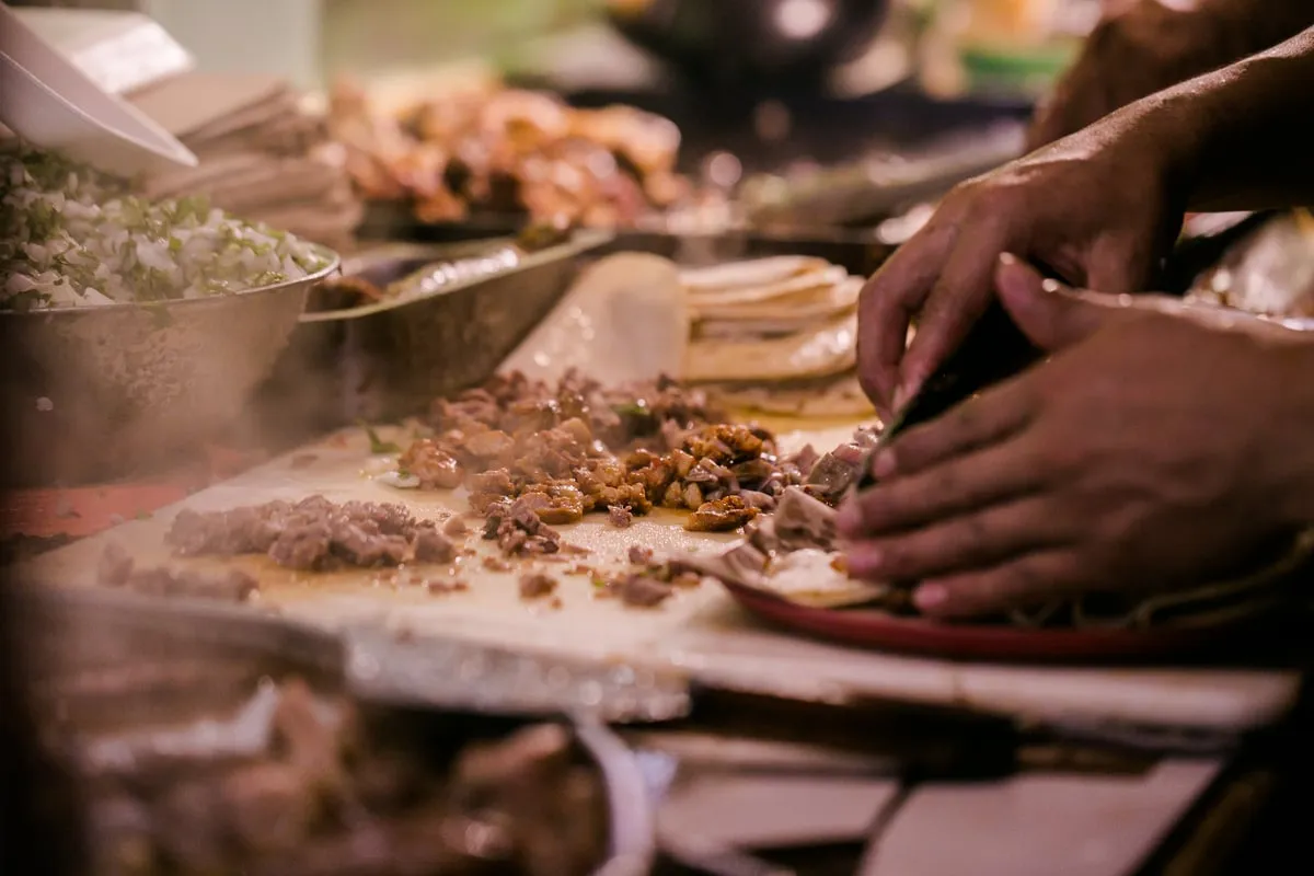 Tacos al pastor being carved and prepared at a local taquería on a food tour in Playa del Carmen, Mexico