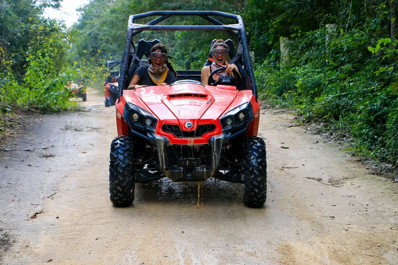 Two travelers driving an off-road dune buggy along a jungle trail on a cenote tour near Playa del Carmen, Mexico